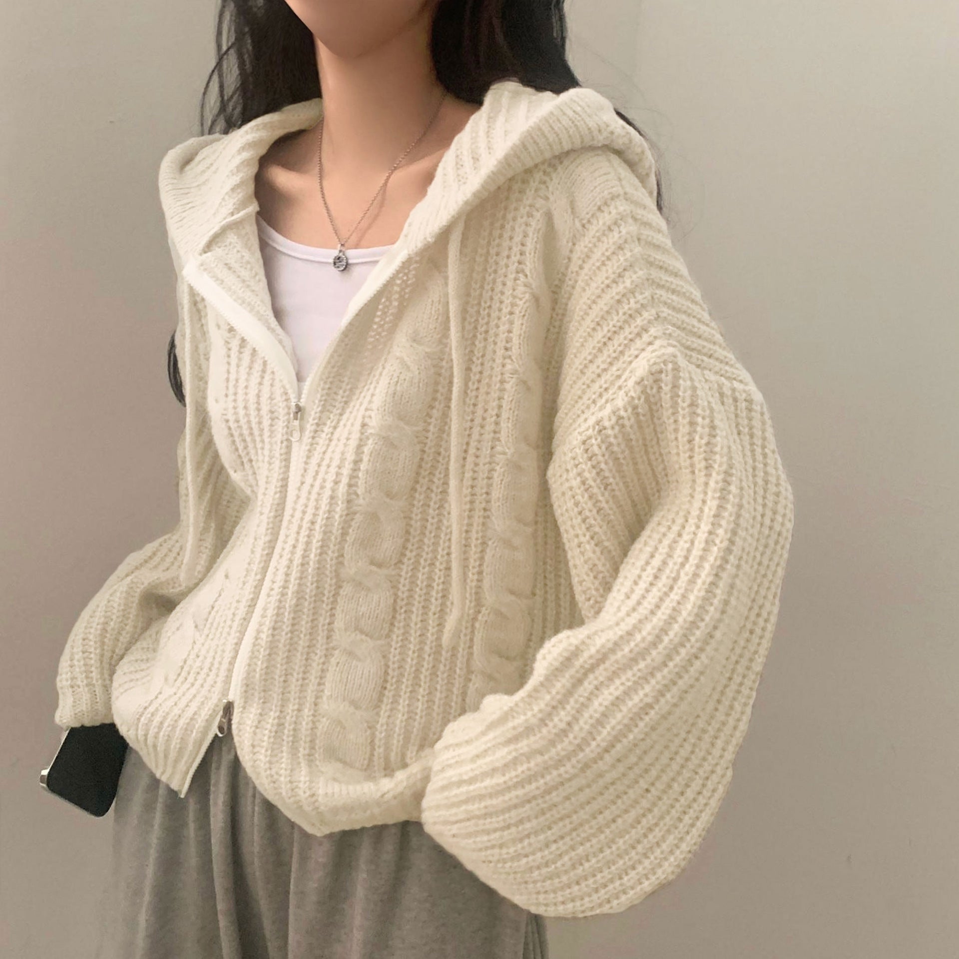 Person wearing a cream knitted cardigan against a plain background