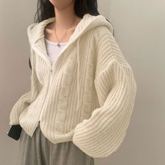 Person wearing a cream knitted cardigan against a plain background