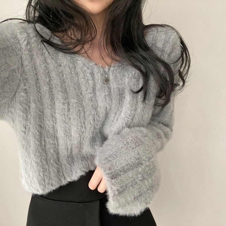 Person wearing a gray textured sweater against a plain background