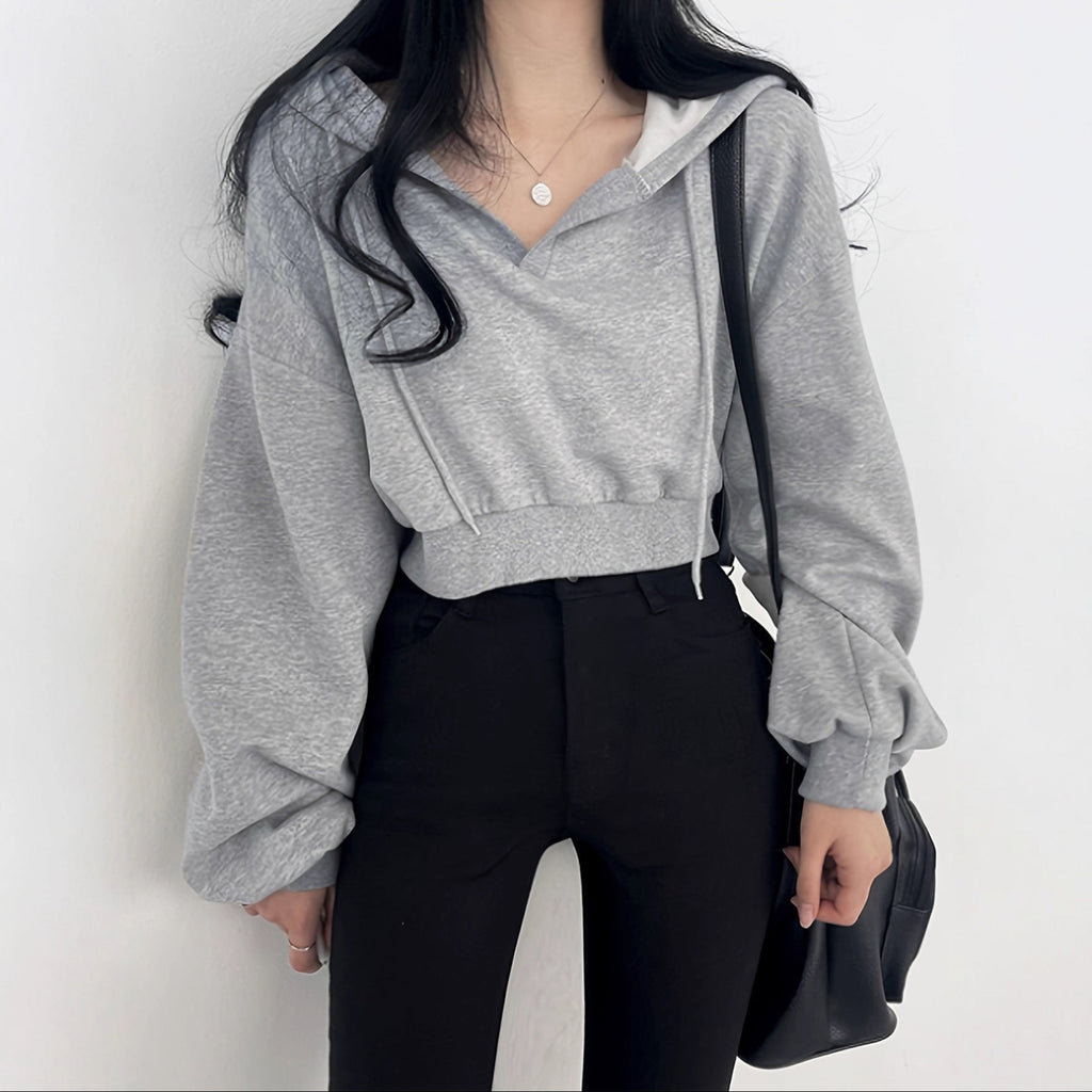 Person wearing a gray hoodie and black pants against a white background