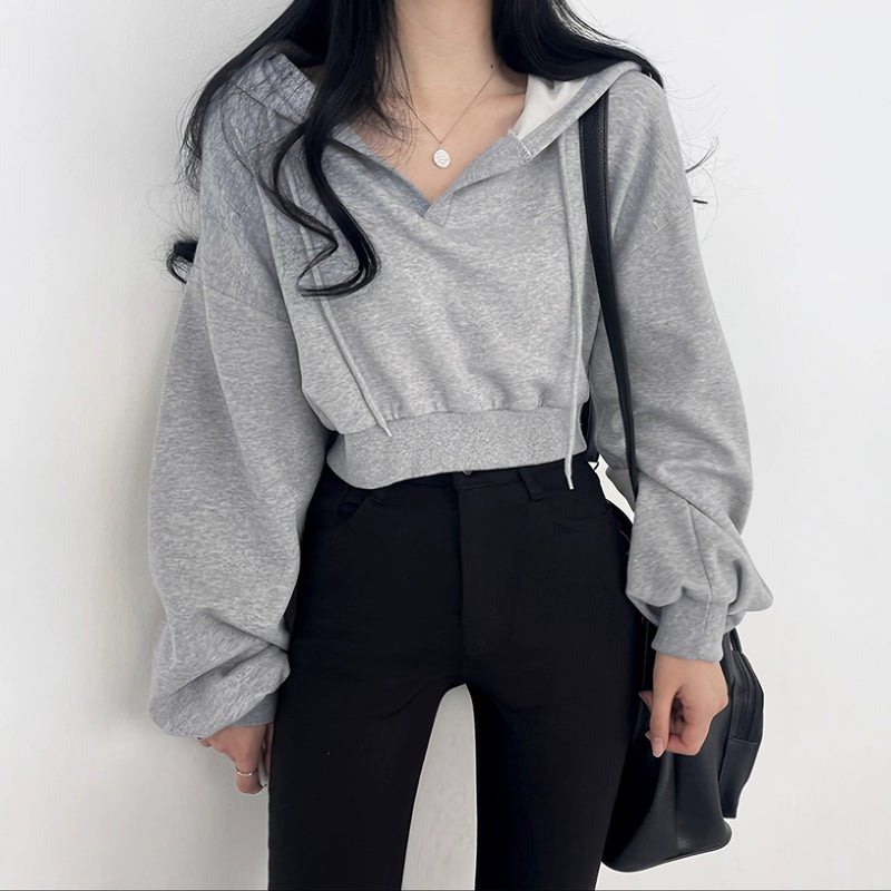 Person wearing a gray hoodie and black pants against a white background