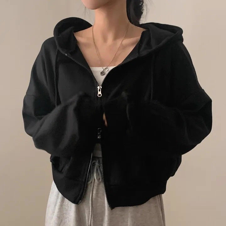 Person wearing a black zip-up hoodie against a plain background