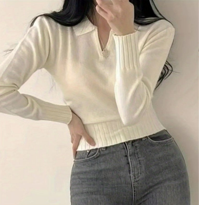 Person wearing a cream sweater and gray jeans against a plain background