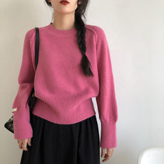 Person wearing a pink sweater and black skirt against a plain background