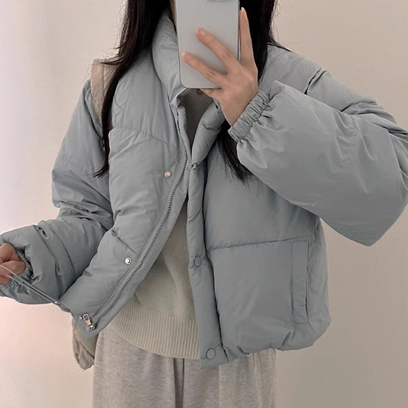 Person wearing a light gray puffer jacket against a plain background