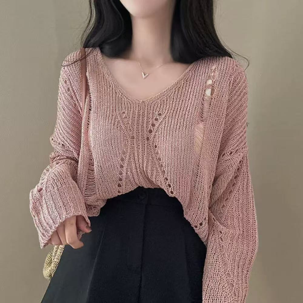 Person wearing a pink knit sweater against a neutral background