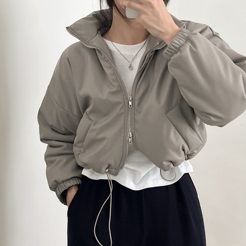 Person wearing a gray jacket over a white shirt with a plain background