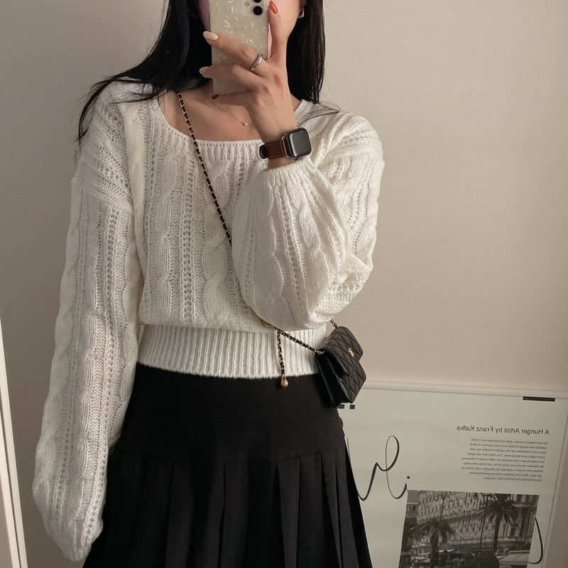Person wearing a white knit sweater and black skirt, holding a phone.