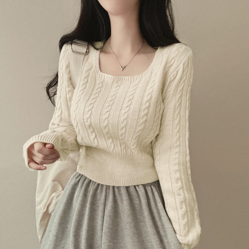 Person wearing a cream cable knit sweater and gray skirt against a beige background