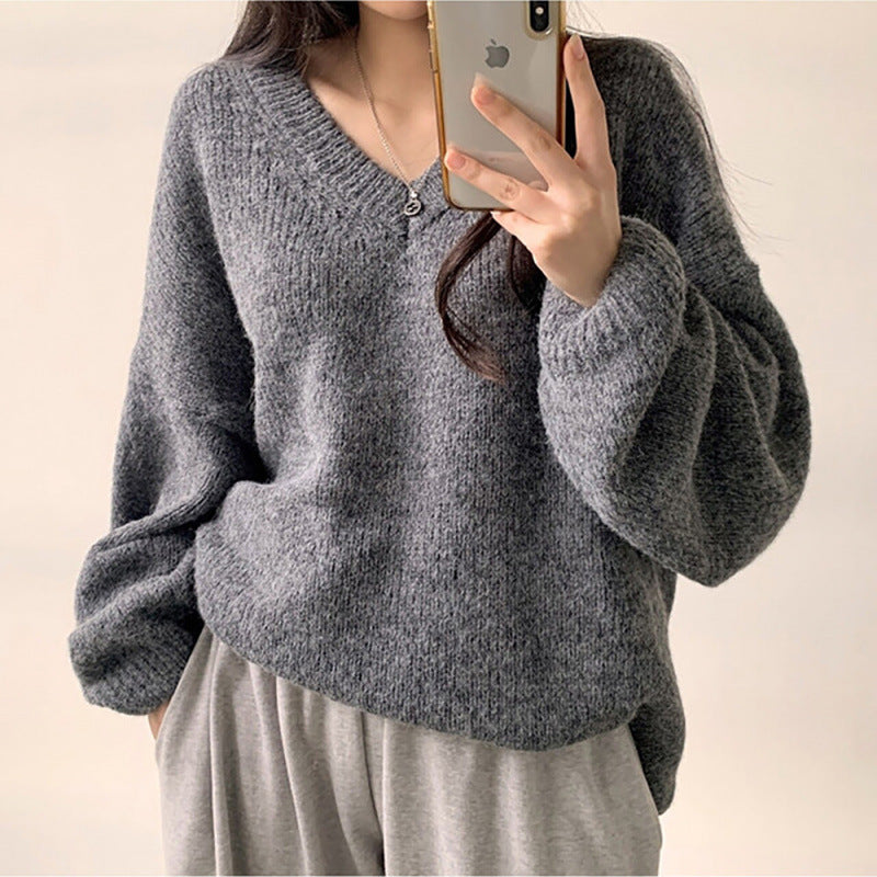 Person wearing a gray sweater taking a mirror selfie.