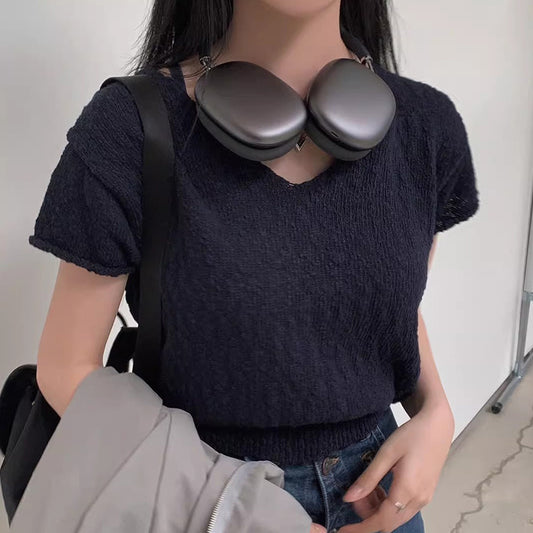 Person wearing a dark blue textured sweater with a black bag over their shoulder.