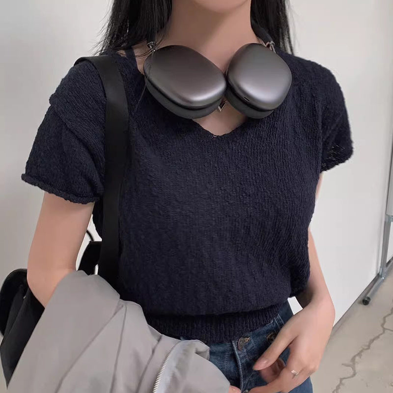 Person wearing a dark blue textured sweater with a black bag over their shoulder.