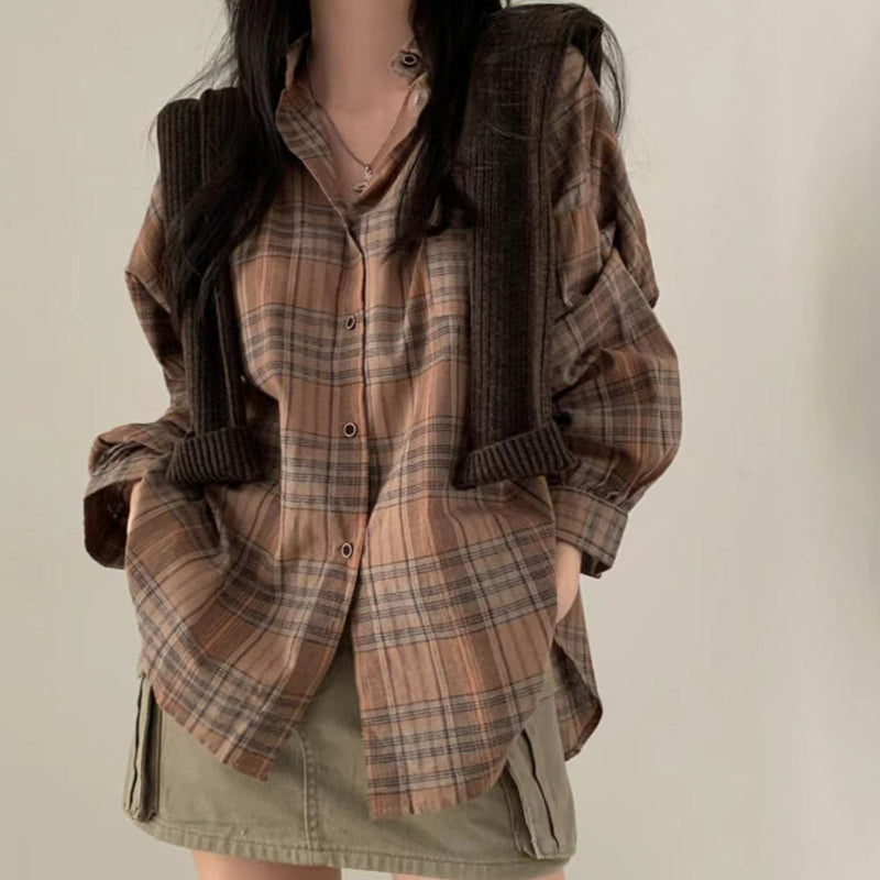 Person wearing a plaid shirt and brown jacket against a plain background