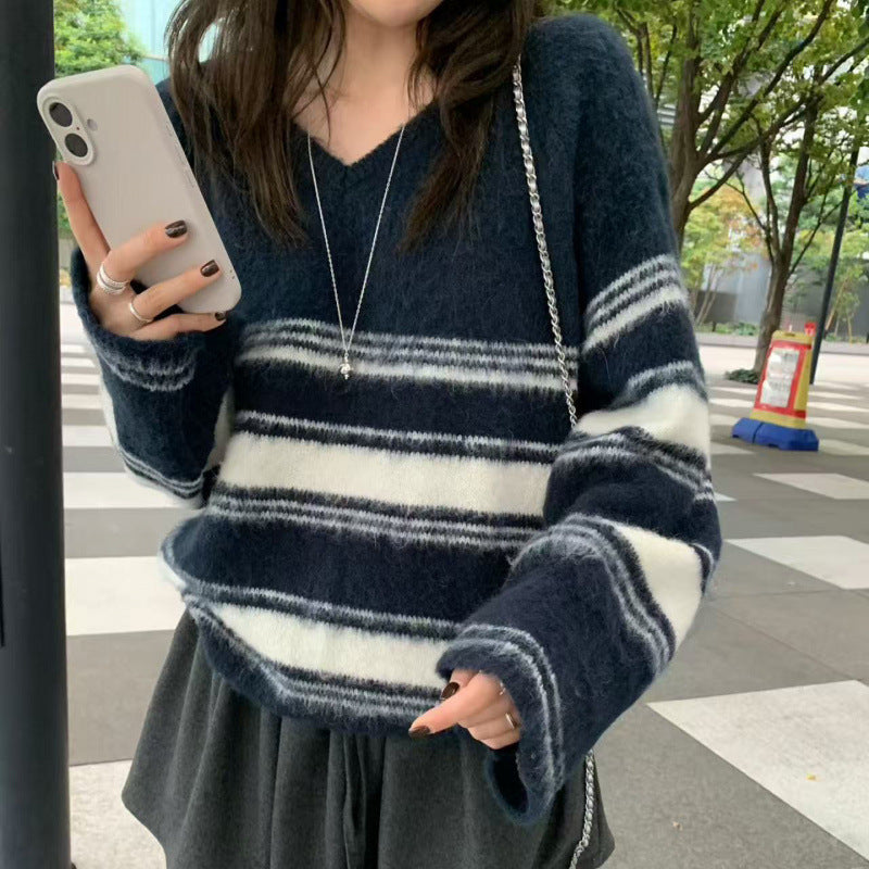 Person wearing a blue and white striped sweater on a city street.