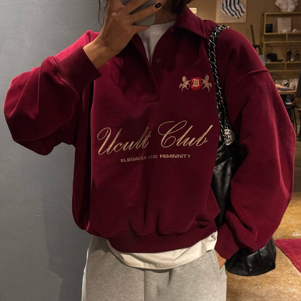 Person wearing a red sweatshirt with 'Ucult Club' text and logo, holding a phone.