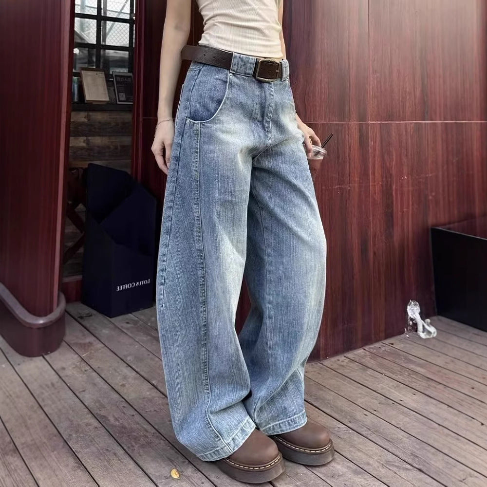 Person wearing wide-leg jeans and brown shoes on a wooden floor.