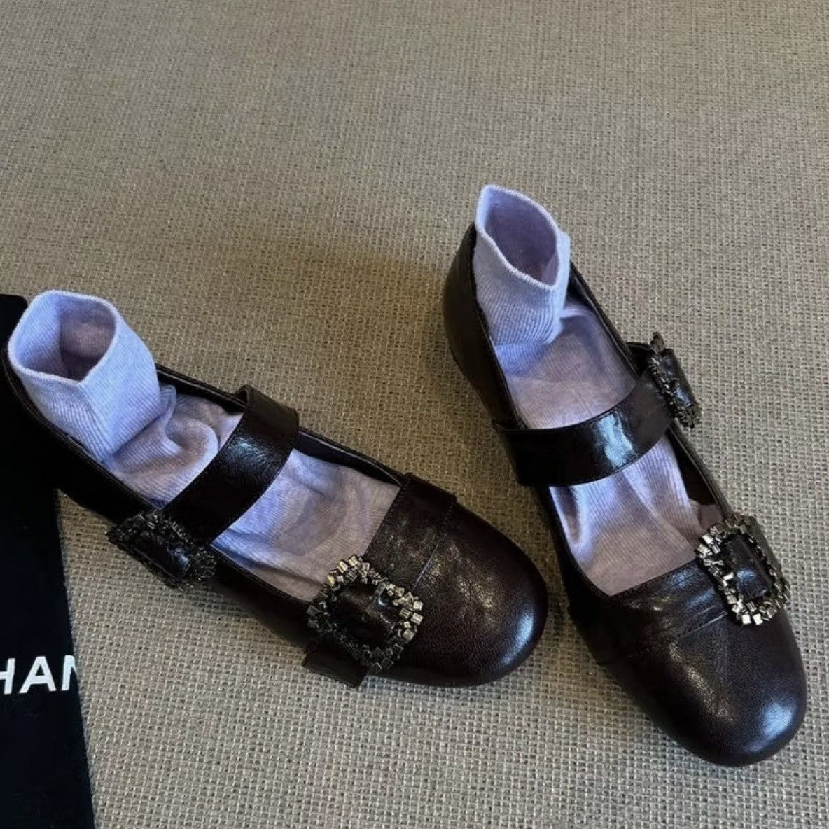 Pair of black shoes with decorative buckles on a textured surface