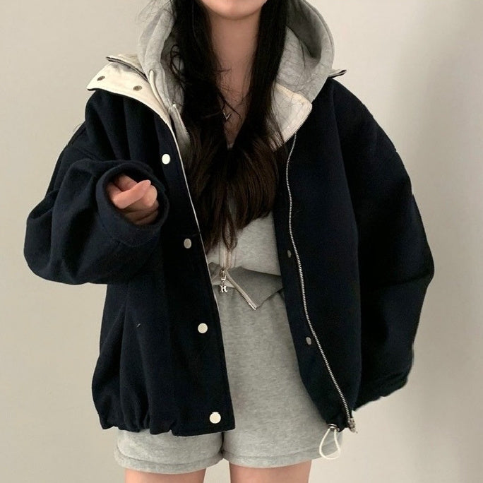 Person wearing a black jacket with white buttons on a plain background