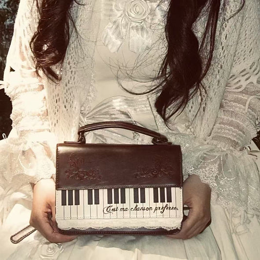 Person holding a brown handbag with piano keyboard design and text.