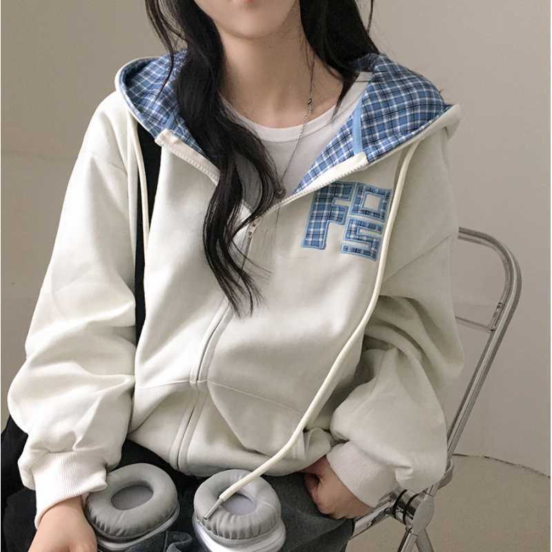 Person wearing a white hoodie with blue plaid lining, sitting on a chair.