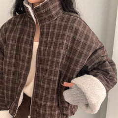 Person wearing a plaid jacket with shearling-lined sleeves against a neutral background