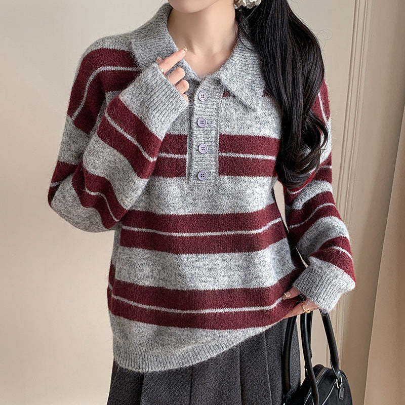 Person wearing a gray and red striped sweater holding a black handbag.