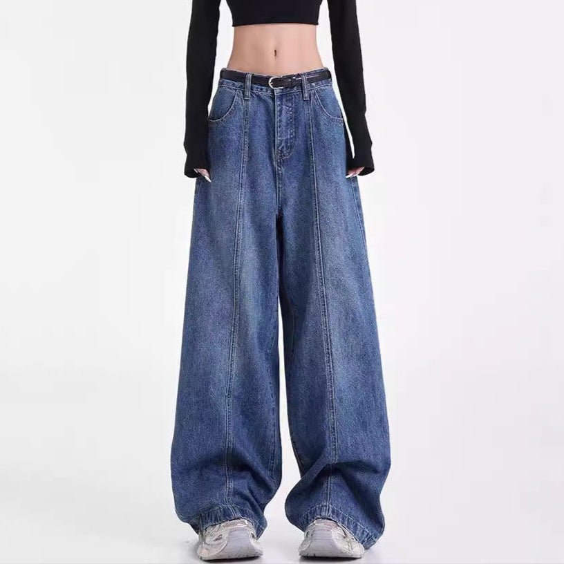 Person wearing a black long-sleeve crop top and blue wide-leg jeans on a white background