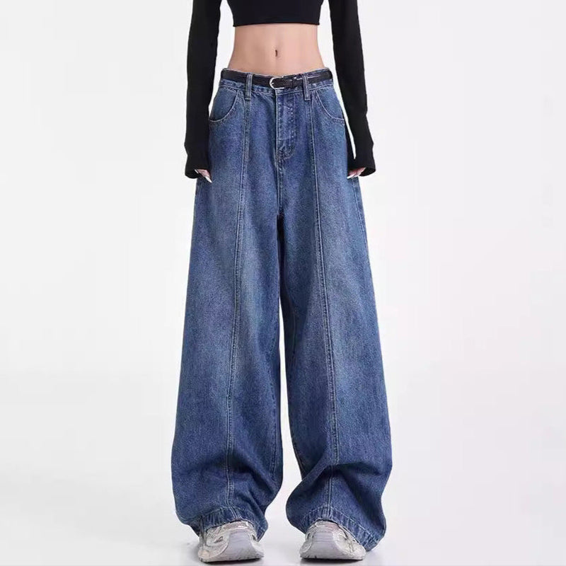 Person wearing a black long-sleeve crop top and blue wide-leg jeans on a white background