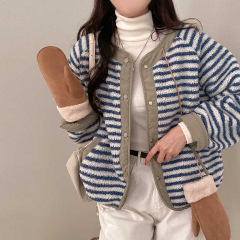 Person wearing a blue and white striped cardigan with brown mittens against a plain background