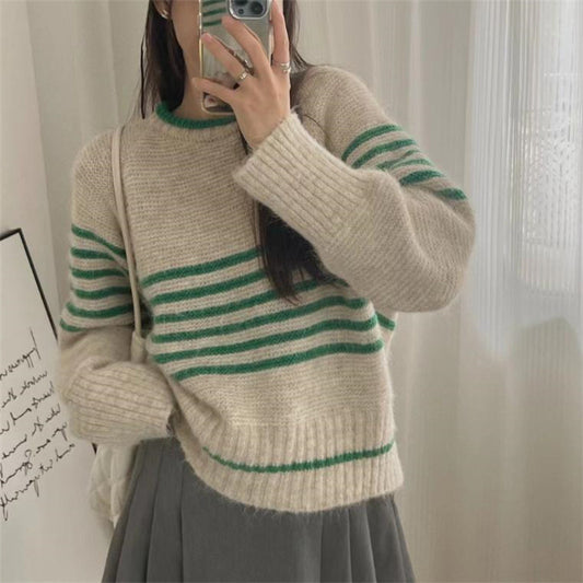 Person wearing a beige sweater with green stripes taking a mirror selfie.