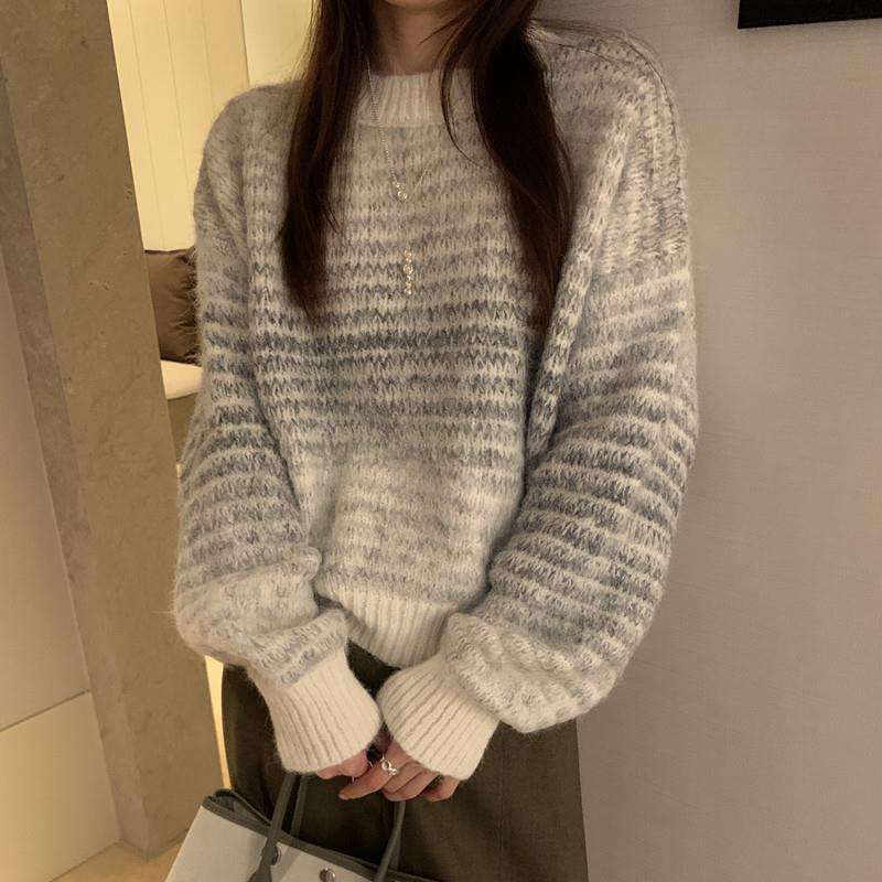 Person wearing a gray and white patterned sweater in an indoor setting