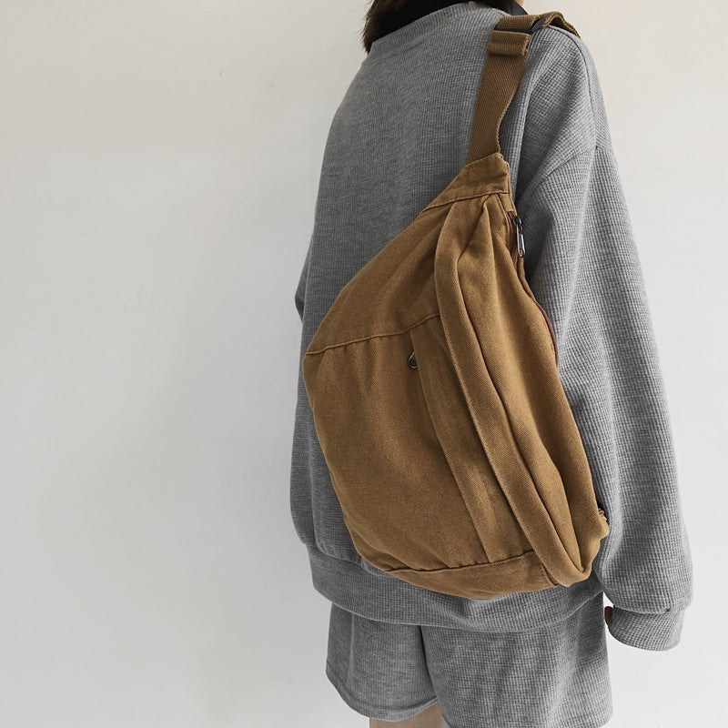 Person wearing a brown sling bag over one shoulder against a plain background