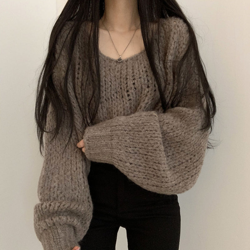 Person wearing a chunky knit sweater against a plain background