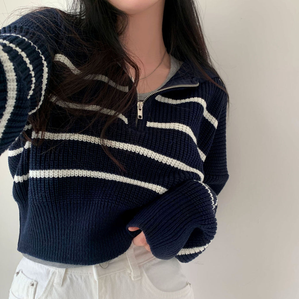 Person wearing a navy blue sweater with white stripes on a plain background
