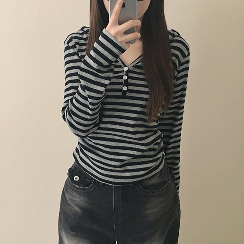 Person wearing a black and gray striped long-sleeve shirt with a plain background