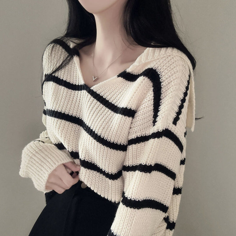 Person wearing a cream sweater with black stripes against a neutral background